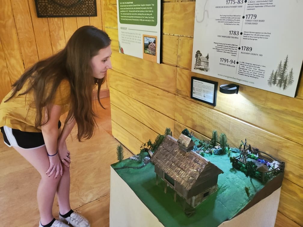 A girl looking intently at the diorama of the Evergreen Heritage Center