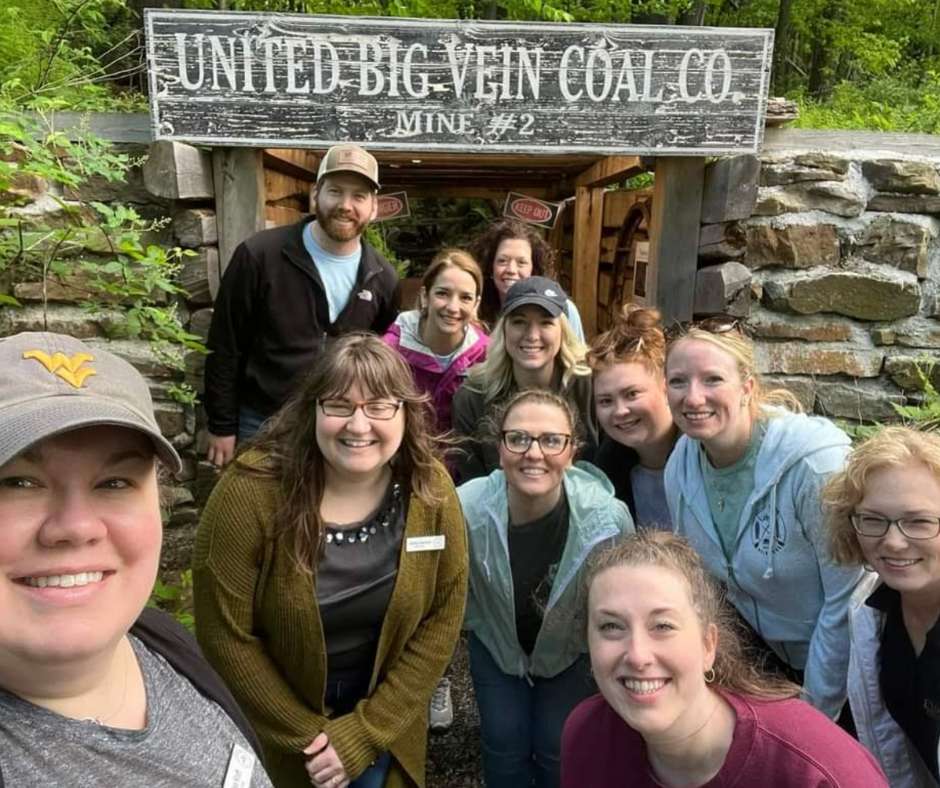 A group of smiling people posing for a photo in front of the mine opening exhibit