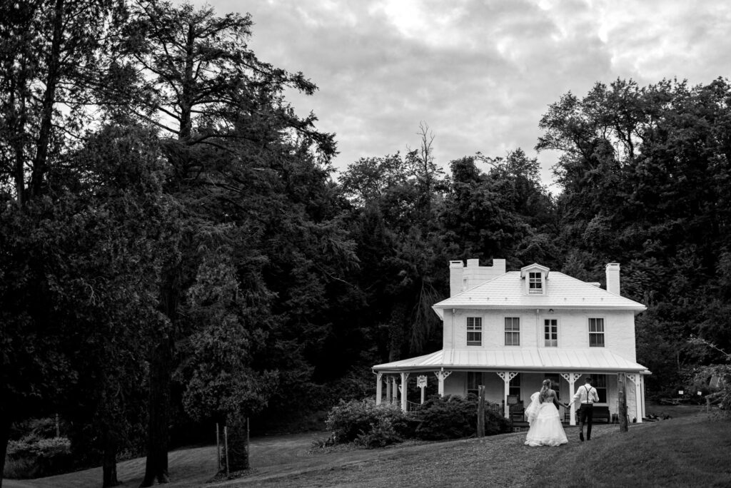 Black-and-white photo of the historic white farmhouse museum building surrounded by trees.